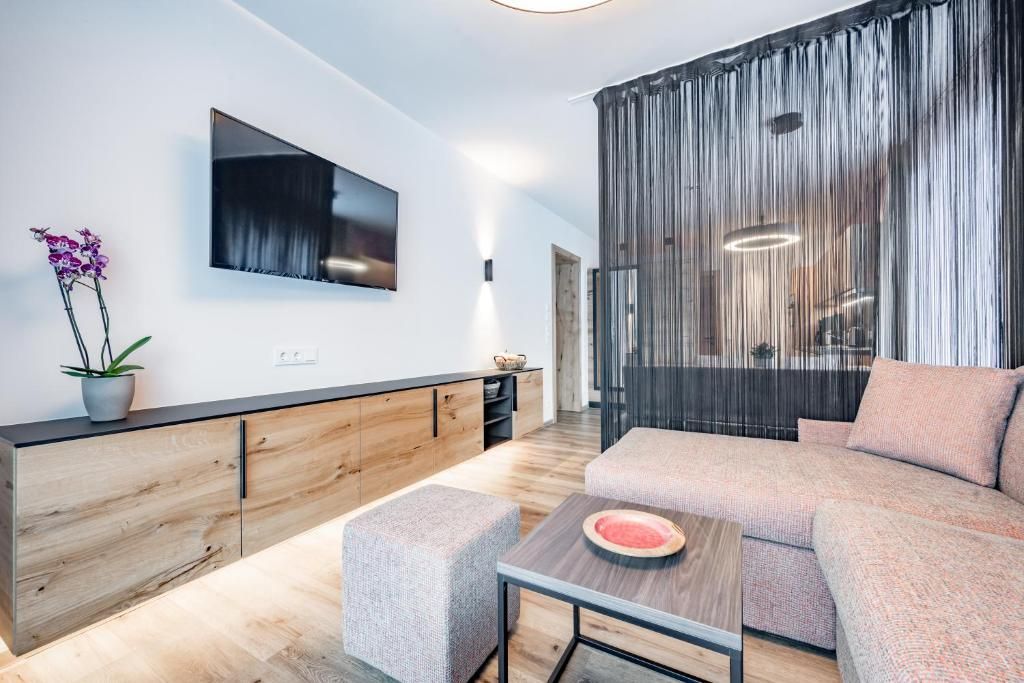 Una sala de estar moderna con un sofá, una mesa de centro y un televisor montado en la pared.