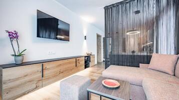 Una sala de estar moderna con un sofá, una mesa de centro y un televisor montado en la pared.
