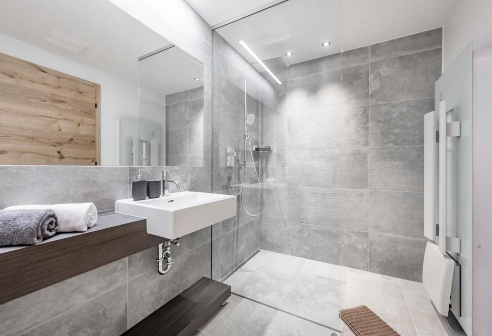 Une salle de bain moderne avec un grand miroir, un lavabo blanc et un espace douche.