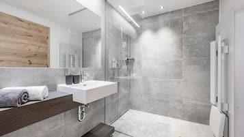 Une salle de bain moderne avec un grand miroir, un lavabo blanc et un espace douche.