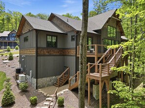 Une cabane avec des fondations en pierre, une terrasse en bois et un escalier menant à un balcon.