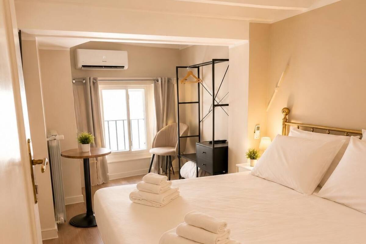 Ein Hotelzimmer mit Bett, Stuhl, Schreibtisch, Heizkörper und Fenster.
