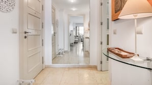 Un couloir avec une cloison en verre, un plateau en bois posé sur une table en verre et une lampe.