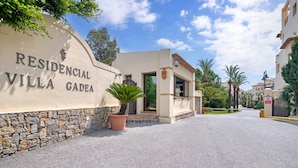 L’entrée d’une villa, avec un mur en pierre, un pot de fleurs et un ciel dégagé.