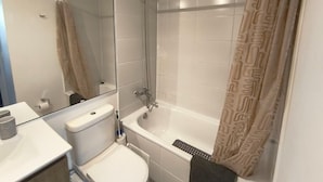 A bathroom with a toilet, sink, mirror, shower, and bathtub. - Oceana Suites Edificio HA (Coquimbo)