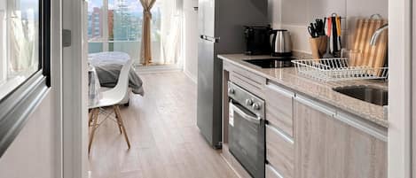 A modern kitchen with a built-in oven, a sink, and a dining area with a table and chairs.