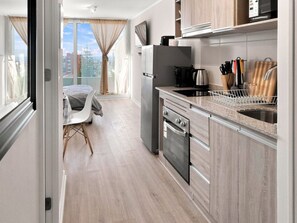 Une cuisine moderne équipée d’un four encastré, d’un évier et d’un coin repas avec une table et des chaises.