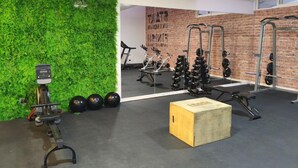 A gym with a green wall, brick wall, and various exercise equipment. - Oceana Suites Edificio HA (Coquimbo)