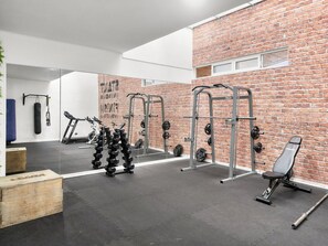 A gym with exercise equipment, a mirror, and a brick wall. - Oceana Suites Edificio HA (Coquimbo)