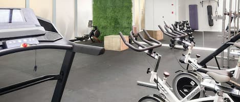 Un gimnasio con bicicletas estáticas, cintas de correr y máquinas de pesas.