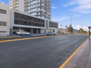 Un immeuble à plusieurs étages doté d’un parking couvert, d’un trottoir pour les piétons et offrant une vue sur un ciel dégagé.