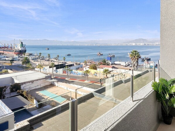 A balcony with a view of a port, ships, and distant mountains. - Oceana Suites Edificio HA (Coquimbo)