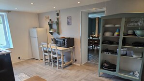 A compact kitchen with a dining area, a built-in shelf unit, and a refrigerator.