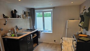 A compact kitchen with a gas stove, sink, and a window with blinds.