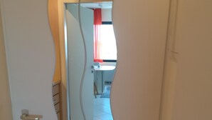 A door with a unique wavy design, leading to a bathroom with a white sink and red curtains. - Pure relaxation on the Baltic Sea: vacation apartment with sandy beach right on the doorstep! (Fehmarn)