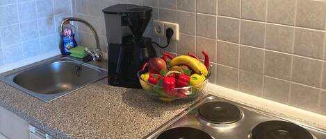 Una cocina con encimera de granito, pileta de acero inoxidable y estufa con cuatro hornallas.