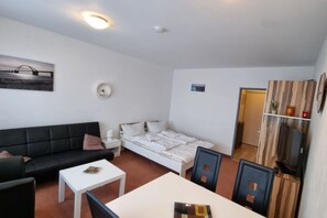 En kompakt bolig med seng, sofa, spisebord og et lille hvidt skab.