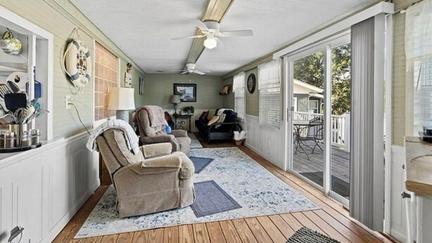 A sunroom with a ceiling fan, a sliding glass door leading to a deck, and a seating area with a sofa and two recliners. - Wonderful 3-bedroom house with AC in welcoming Cross Hill (Cross Hill)