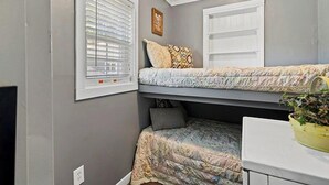 A compact room with a bunk bed, a small table with a plant, and a window with blinds. - Wonderful 3-bedroom house with AC in welcoming Cross Hill (Cross Hill)
