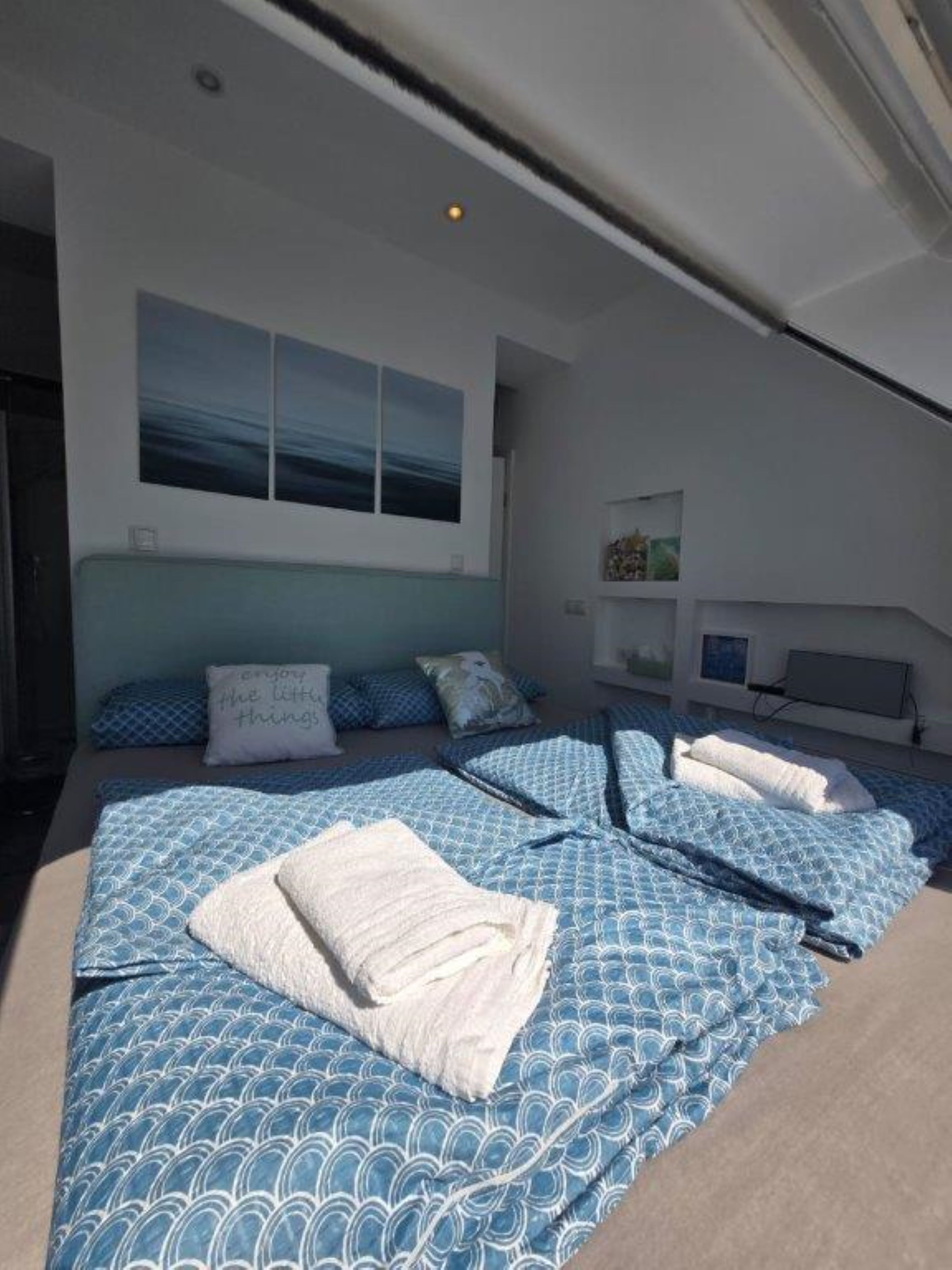 A modern bedroom with a large bed, a headboard, and a painting on the wall.