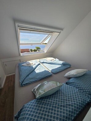 Ein kleines Zimmer mit einem Einzelbett, einem Oberlicht und Meerblick.