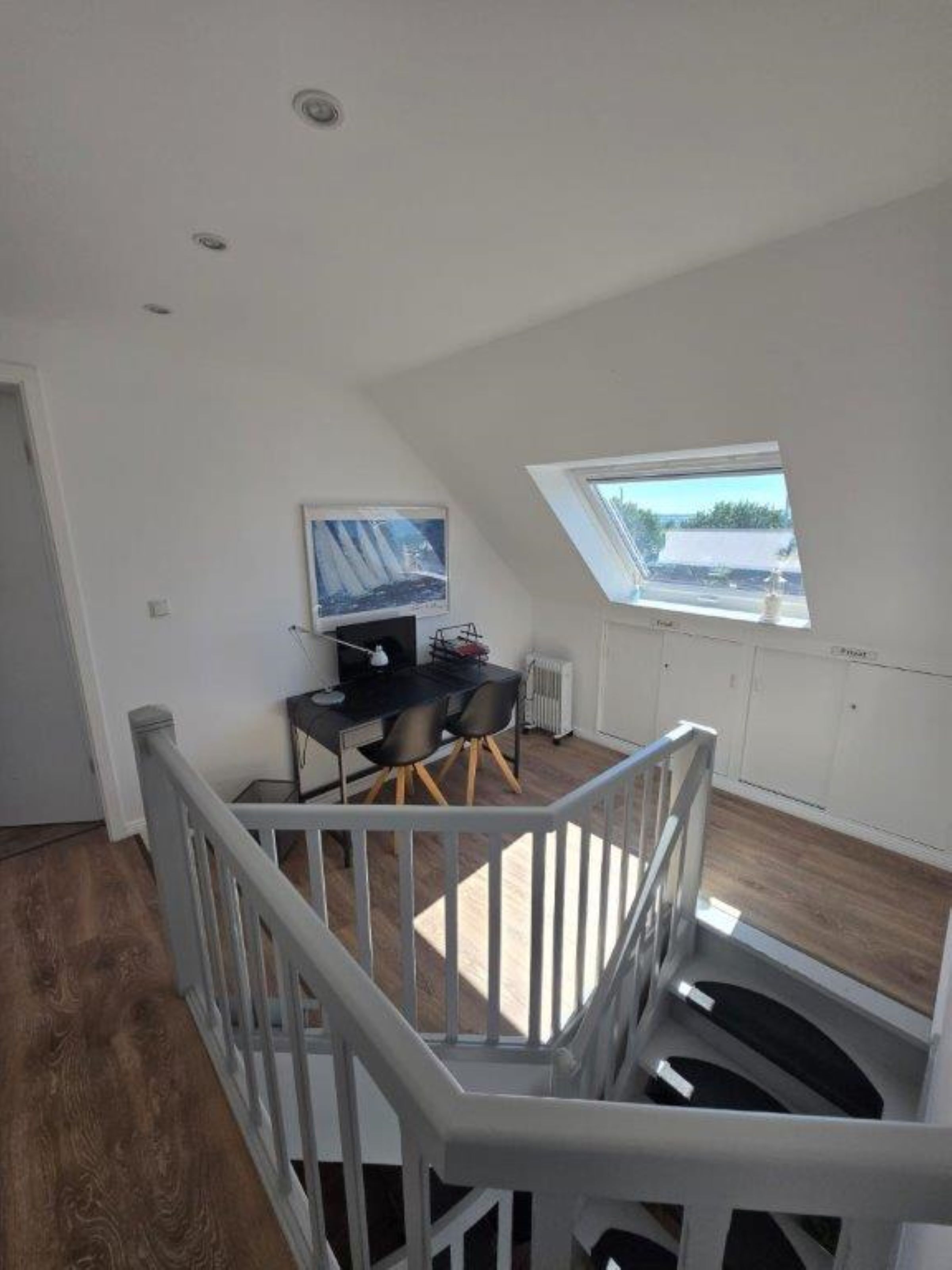 Ruime loft slaapkamer met dakraam, een eethoek met tafel en stoelen, en uitzicht op de omgeving.