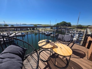 Eine Terrasse mit Sitzgelegenheiten blickt auf einen Yachthafen mit Booten.