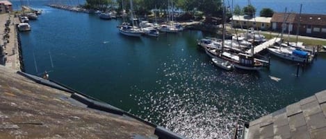 A marina with boats docked, a clear sky, and a distant view of a bridge.