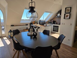 Et moderne k økken med ovenlys, et spiseområde med et rundt bord og en sort stol.