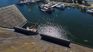 Un puerto deportivo con barcos amarrados, cielo despejado y una isla distante.