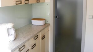 Eine Küche mit weißen Schränken, einer Granit Arbeitsplatte, einem Toaster und einer Tür mit Milchglasfenster.
