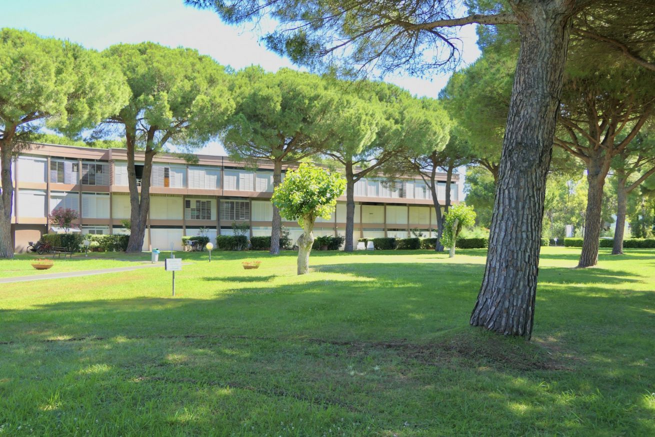 A building with a symmetrical facade, multiple windows, and a well-maintained lawn with trees.