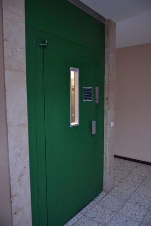 A green elevator door with a small window and a sign. - Baltic Sea love: Your cozy vacation apartment with a fantastic sea view! (Fehmarn)