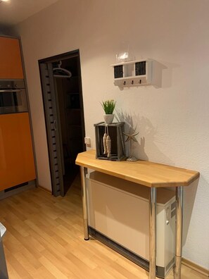 Eine kleine Küche mit Backofen, einer Holz Arbeitsplatte und einem Regal mit einer Pflanze.