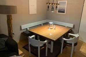 Ein Essbereich mit einem Holztisch, weißen Stühlen, einer Bank und einer Lampe.