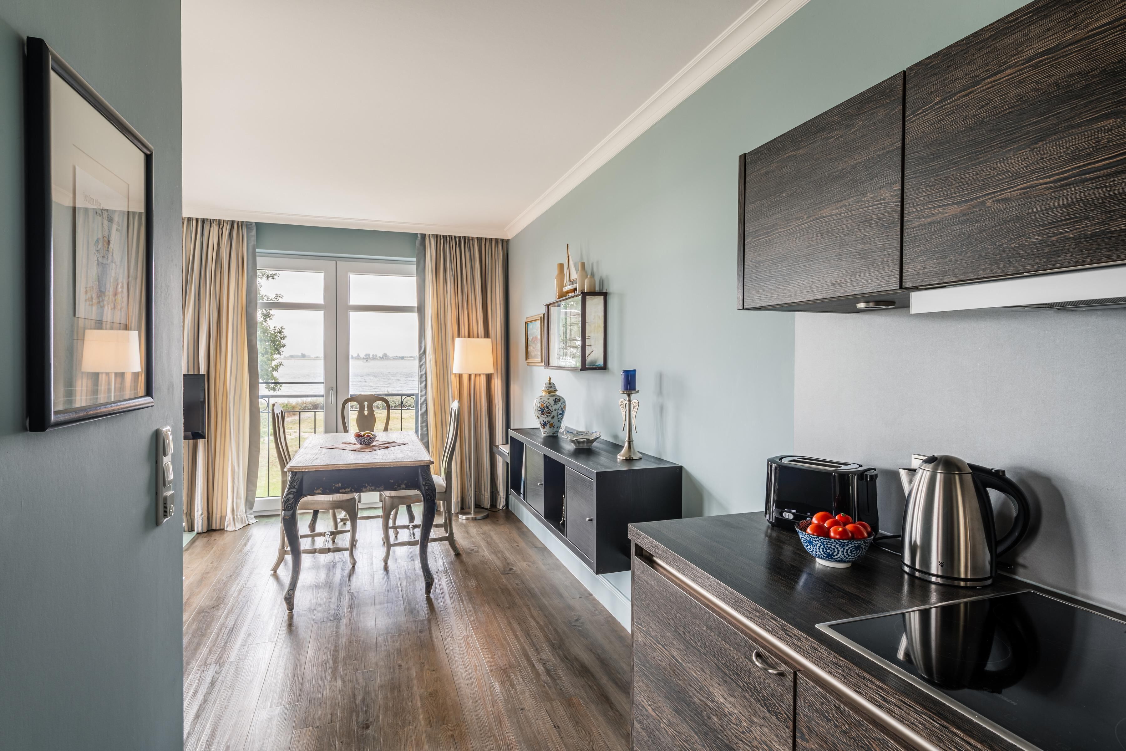 Une cuisine moderne avec des meubles de couleur bois foncé, un plan de travail noir et un coin repas comprenant une table et des chaises.