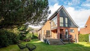 Ein modernes, zweistöckiges Haus mit Backsteinfassade, großen Fenstern und einem gepflegten Rasen.