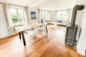 A modern living space with a dining area, a sofa set, and a wood-burning stove. - Seehaus in Orth on Fehmarn by the sea—filming location for "Schwanitz" (Fehmarn)