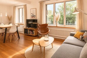 A modern living room with a sofa, a dining table with chairs, a television, and a bookshelf. - Seehaus in Orth on Fehmarn right by the sea - filming location "Schwanitz" (Fehmarn)
