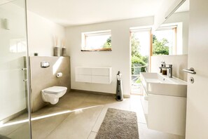 A modern bathroom with a glass shower enclosure, a toilet, a bidet, and a sink with a mirror. - Seehaus in Orth on Fehmarn right by the sea - filming location "Schwanitz" (Fehmarn)