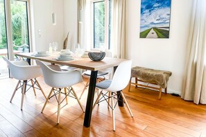 A dining area with a wooden table, white chairs, and a bench. - Seehaus in Orth on Fehmarn right by the sea - filming location "Schwanitz" (Fehmarn)