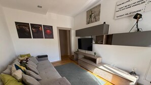 Een moderne woonkamer met een grijze bank, een flatscreen televisie en een minimalistisch design.