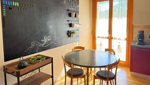 Een moderne keuken met een prikbordwand, houten kastjes en een eethoek met een ronde tafel en stoelen.