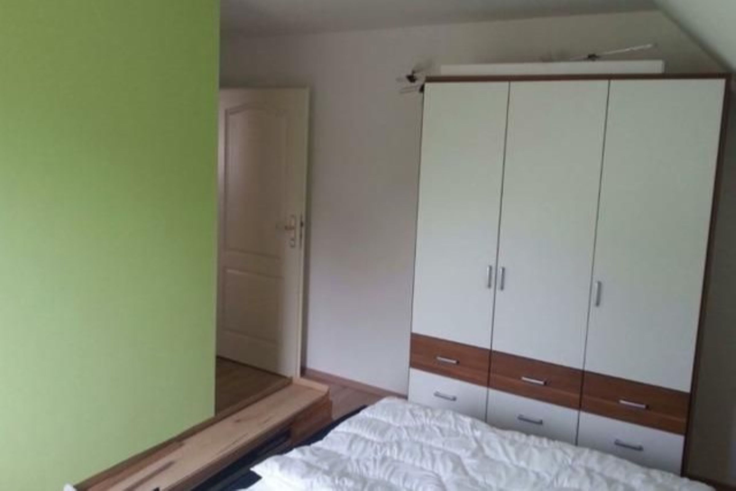 Une chambre à coucher avec un lit, une armoire et une porte.