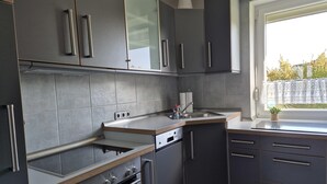 Une cuisine moderne avec des meubles gris, un four en acier inoxydable et une fenêtre donnant sur l’extérieur.