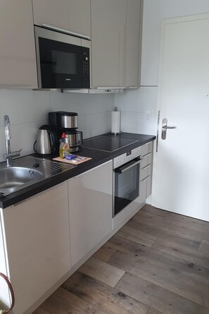 A modern kitchen with a built-in microwave, coffee maker, and oven. - Only 40 m to the Baltic Sea - stylish vacation apartment on Fehmarnsund with terrace (Fehmarn)