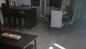 A modern kitchen with built-in appliances, a dining area with a table and chairs, and a living area with a sofa and coffee table. - Beach residence Vogelflug App. 10 - spacious & close to the beach (Fehmarn)
