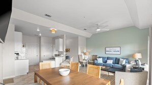 Amplia sala de estar con una mesa de comedor, sofás y una cocina al fondo.