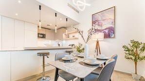 Une cuisine moderne avec un coin repas, comprenant une table en marbre, des chaises grises et des luminaires au design contemporain.