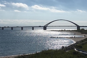 A large bridge spanning a body of water with a clear sky above. - A relaxing beachfront vacation—a vacation apartment with a view of the sea! (Fehmarn)